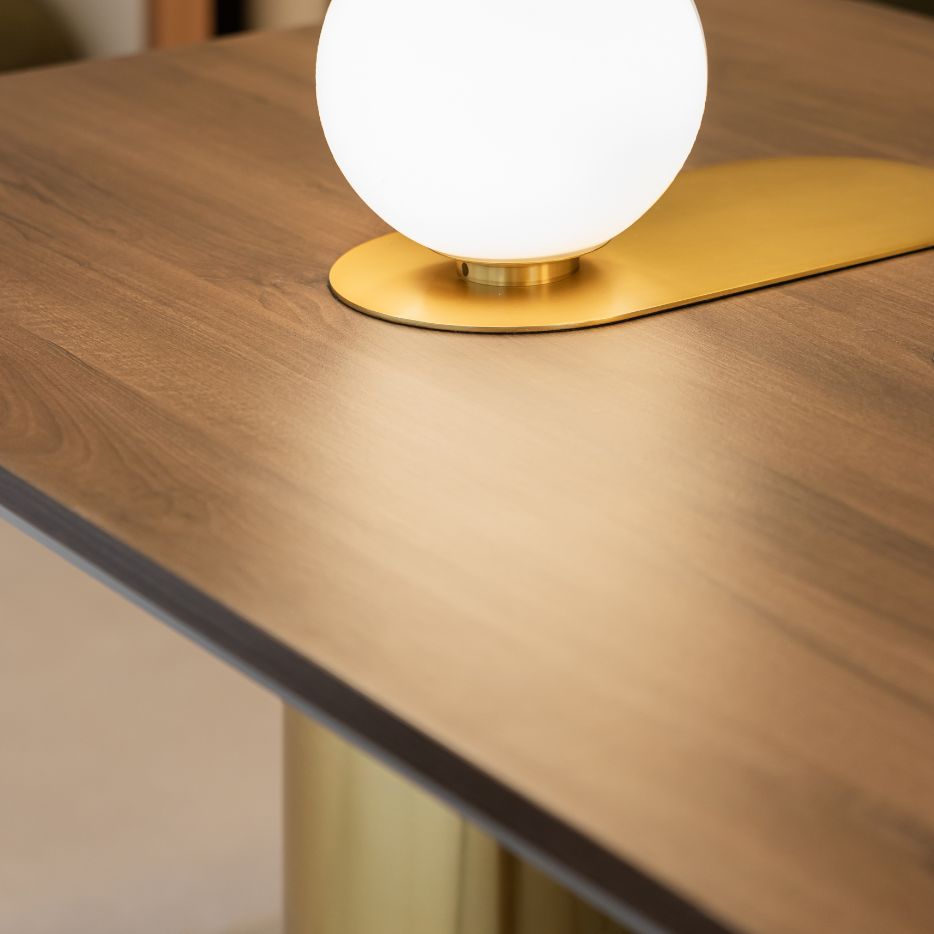 Modern office meeting table with warm wood finish, gold base lamp, and integrated power outlets – premium workspace design.